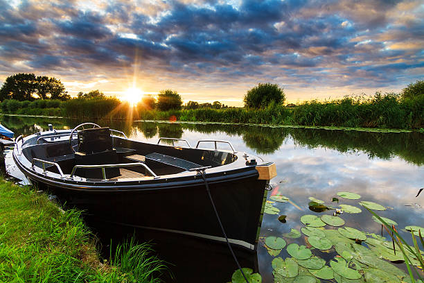 Sloep aan de oever bij zonsondergang